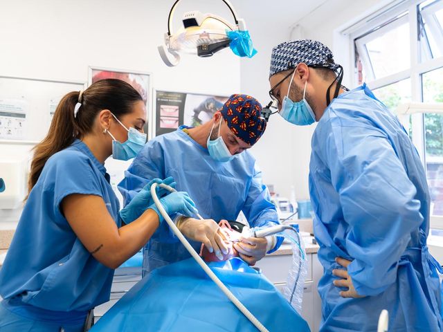 The implant team placing an implant, with a dental nurse assisting